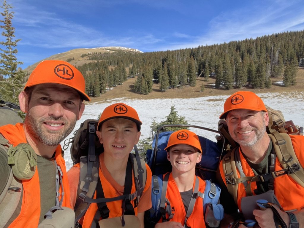 Four hunters wearing the HuntLeague hunter orange hat in the mountains